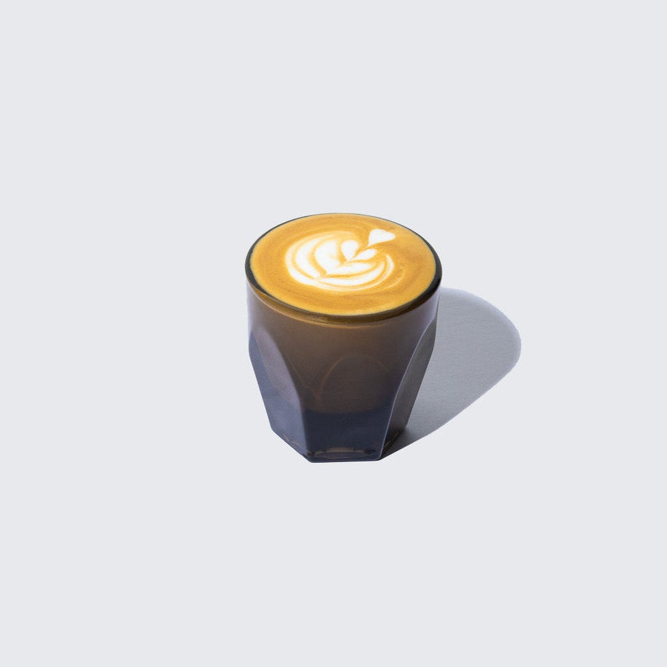 KAFE espresso shot in a clear glass cup with a coffee art design on a white background